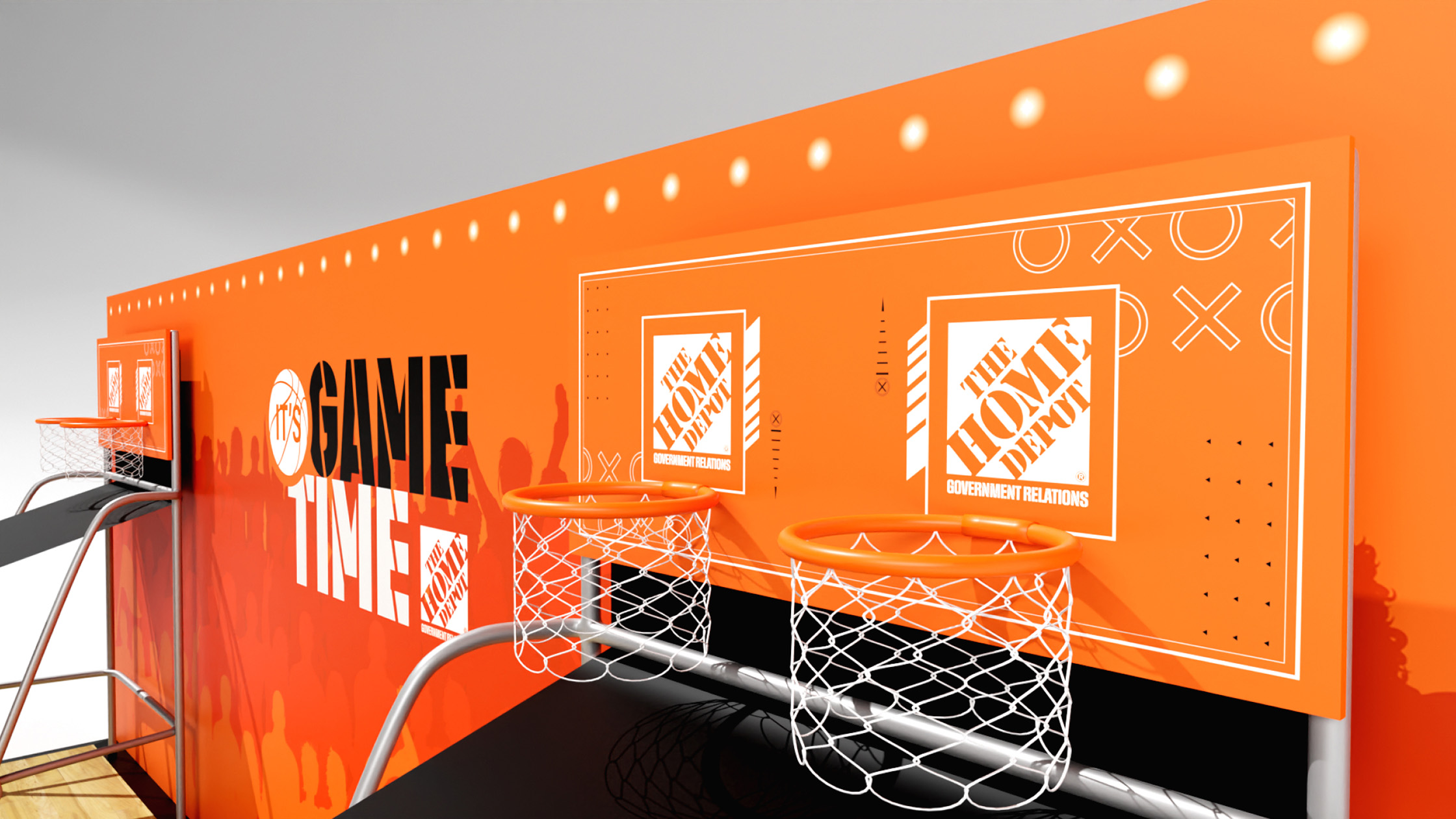 An orange basketball game setup with two hoops and backboards, branded with The Home Depot logo. The backboards feature white lines and graphics. The background wall reads “It’s Game Time” in large black and white letters against an orange backdrop.