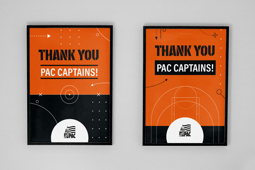 Two framed posters on a wall with identical designs. They have an orange and black color scheme with white accents, and both say, "THANK YOU PAC CAPTAINS!" The PAC logo is at the bottom center of each poster. Various shapes and lines decorate the backgrounds.