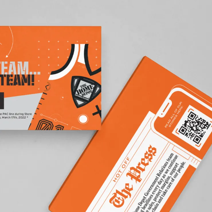 Two orange flyers on a gray surface. The left flyer features graphic elements, text reading "The Team!" and a date, March 17th, 2022. The right flyer resembles a newspaper cover with the text "The Press," a QR code, and smartphone outline near the top right corner.