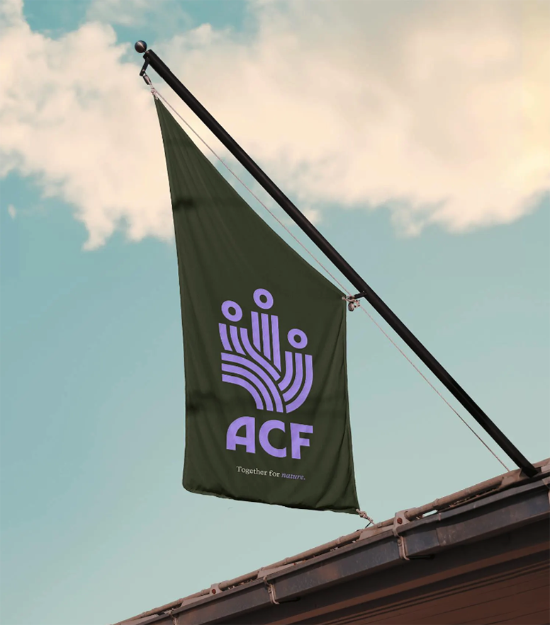 A green flag displaying the acronym "ACF" and a logo with five connected lines ending in circles, raised on a flagpole against a background of soft clouds in a blue sky. The slogan "Together for nature." is printed below the logo.