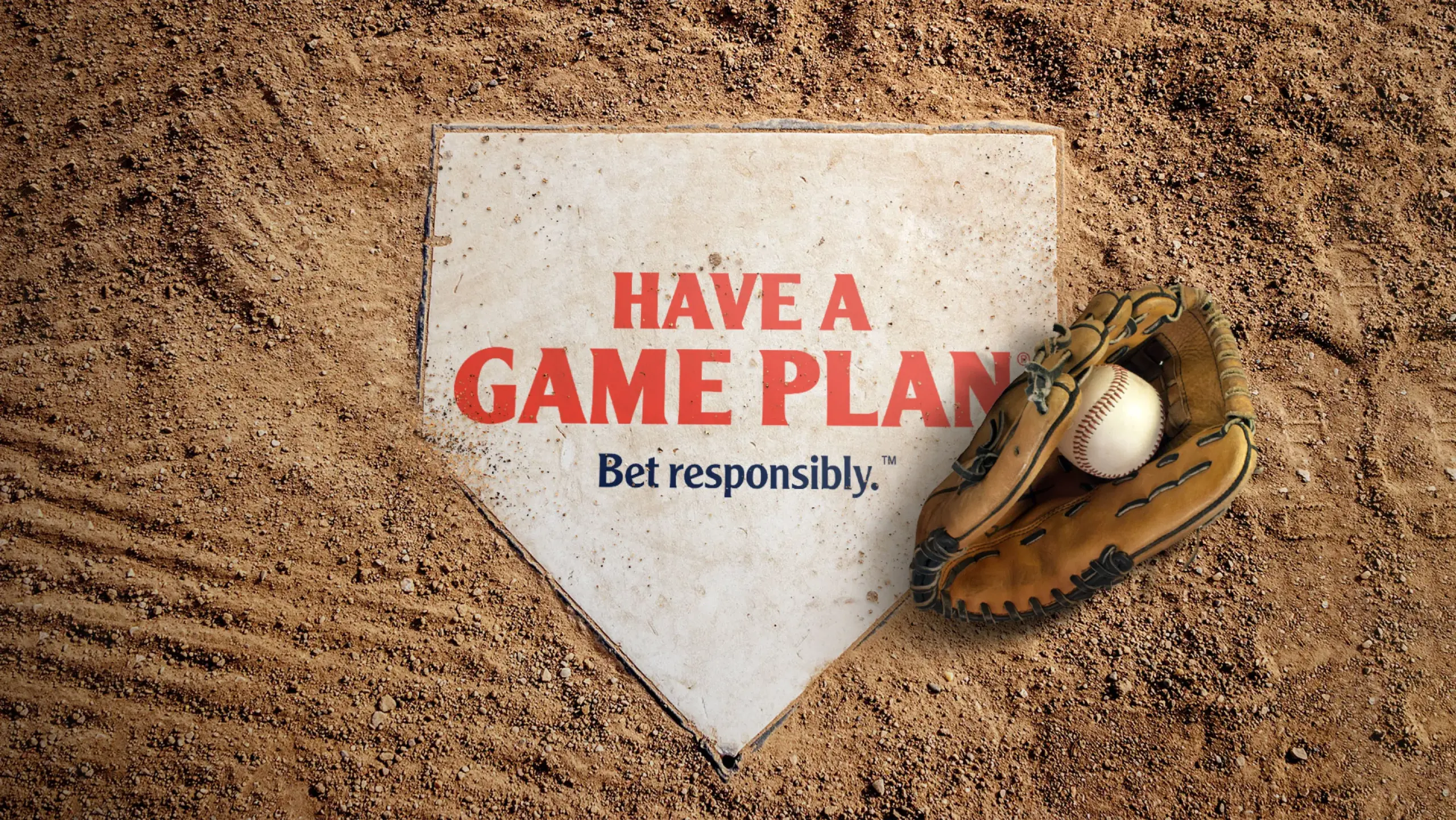 Home plate with the message "Have A Game Plan. Bet responsibly." is written in red and blue text. A baseball glove holding a baseball rests on home plate, surrounded by a dirt field.