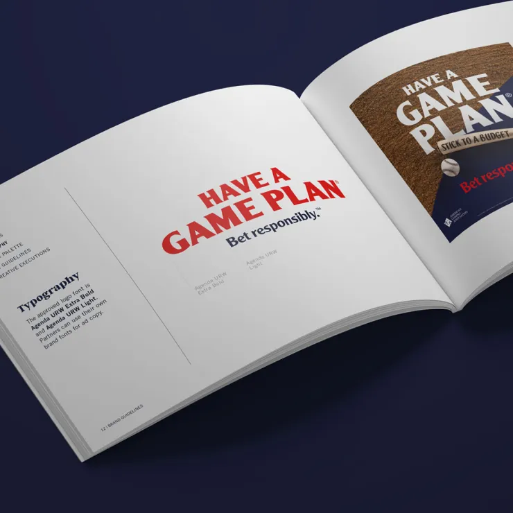 An open booklet on a dark surface shows a page with bold red text that reads "HAVE A GAME PLAN" and "Bet responsibly" beneath it. Another page displays design details and typography guidelines for the same campaign.
