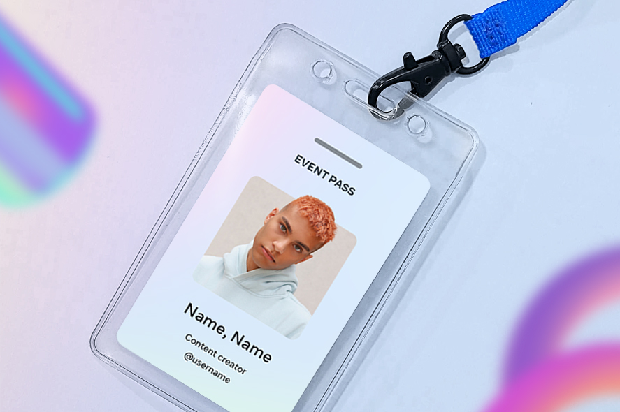 A clear plastic badge holder with a blue lanyard contains an event pass. The pass displays a photo of a person with light orange curly hair, wearing a grey hoodie, the text "EVENT PASS," "Name, Name," and "Content Creator @username". The background has colorful blurred shapes.