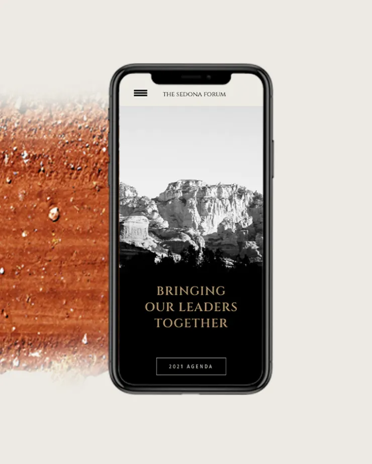 A smartphone showcases a black and white image of a mountainous landscape with "THE SEDONA FORUM" at the top and "BRINGING OUR LEADERS TOGETHER" below it. The background features a close-up, textured surface with reddish-brown hues and small droplets, creating striking digital impressions.