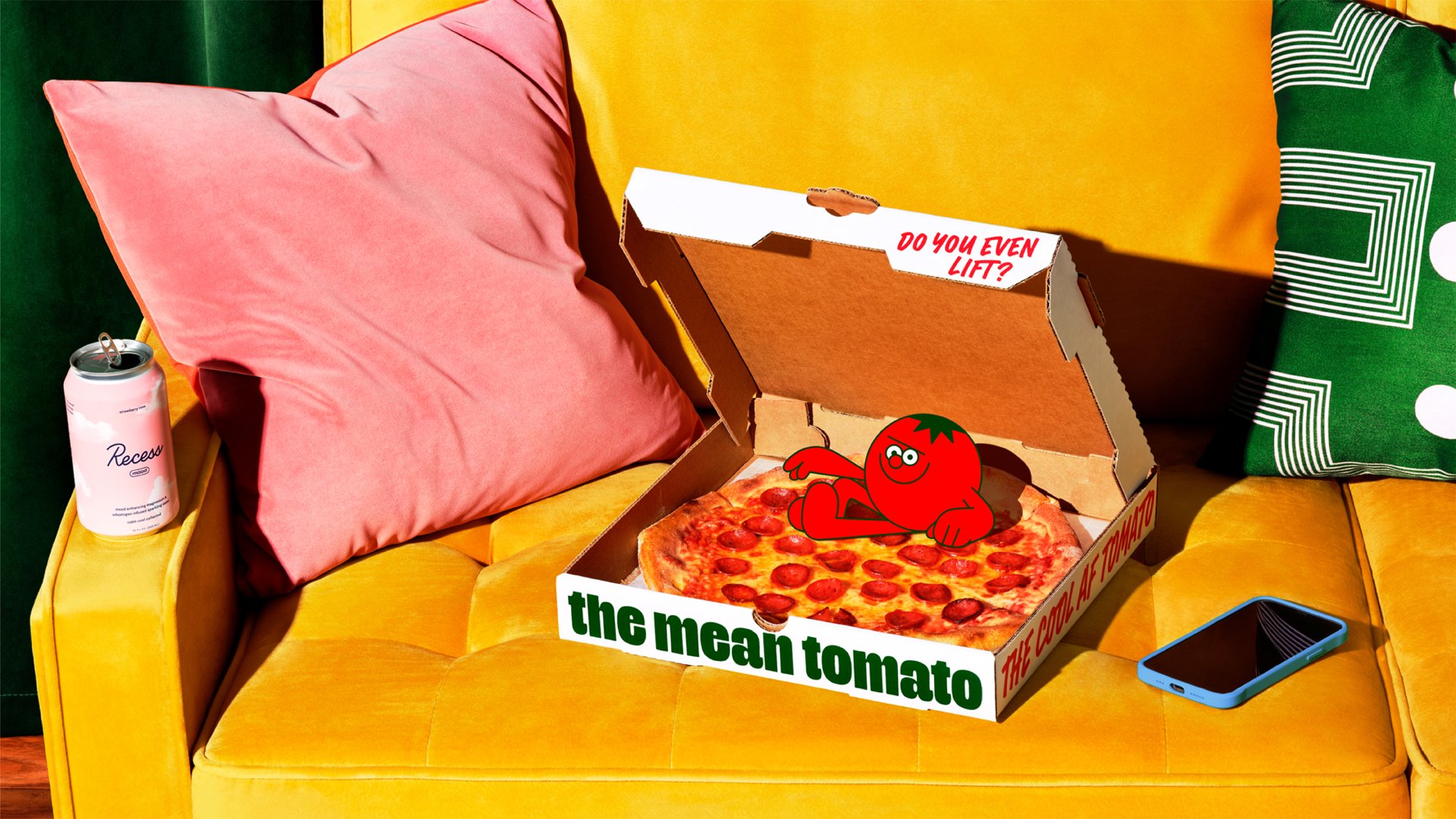 A half-eaten pepperoni pizza in an open box labeled "the mean tomato" is on a yellow couch. The inside of the box lid reads "DO YOU EVEN LIFT?" A pink pillow, a green patterned pillow, a phone, and a can of "Rossy" are also on the couch.