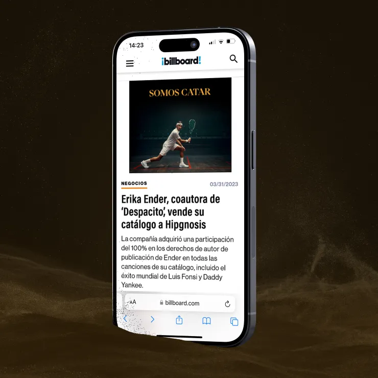 A smartphone displaying a news article from the "Billboard" website in Spanish. The article headline mentions Erika Ender selling her music catalog to Hipgnosis. The phone screen shows the time as 14:23 and has a dark background.