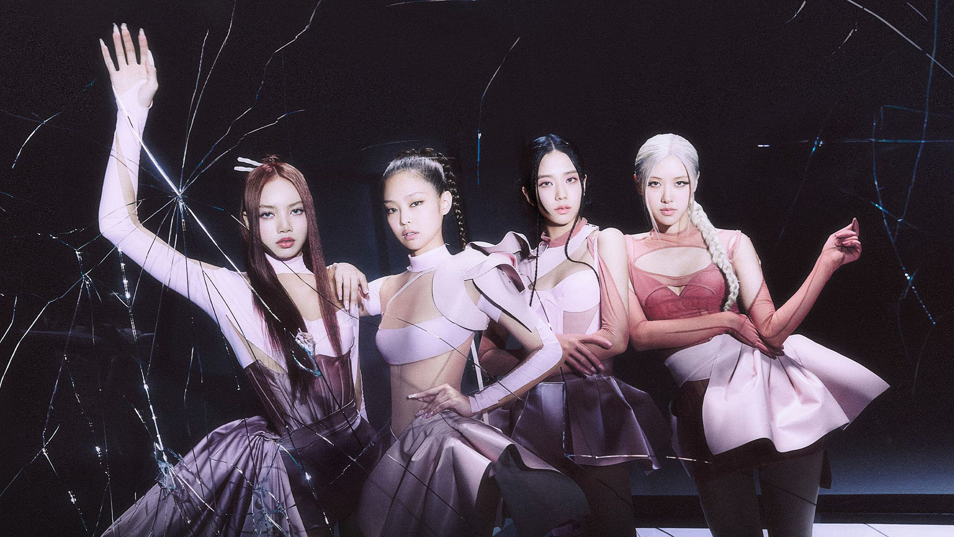 Four women stand confidently in stylish, futuristic outfits against a dark, fractured mirror backdrop. They wear shades of pink and purple, with sleek hairstyles, exuding a sense of unity and strength.